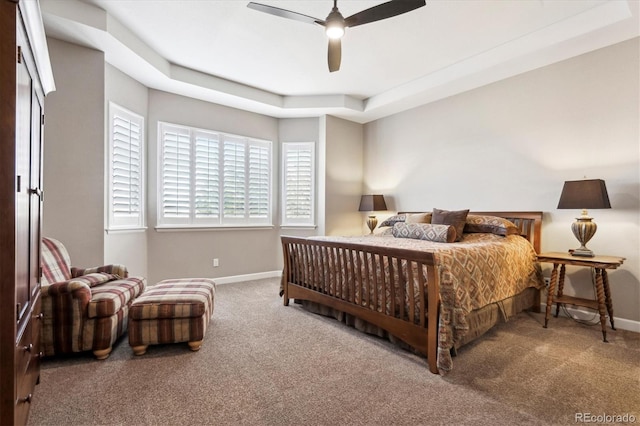 carpeted bedroom with a raised ceiling and ceiling fan