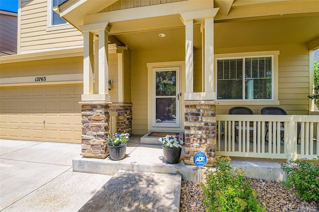 12763 E 105th Pl, Commerce City, CO 80022 - view of exterior entry with a porch, stone siding, driveway, and an attached garage