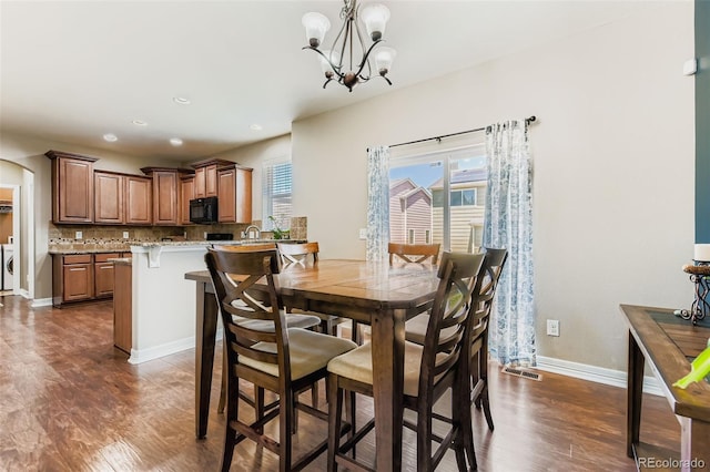 12763 E 105th Pl, Commerce City, CO 80022 - dining room with washer and dryer, dark wood-style floors, healthy amount of natural light, arched walkways, and recessed lighting
