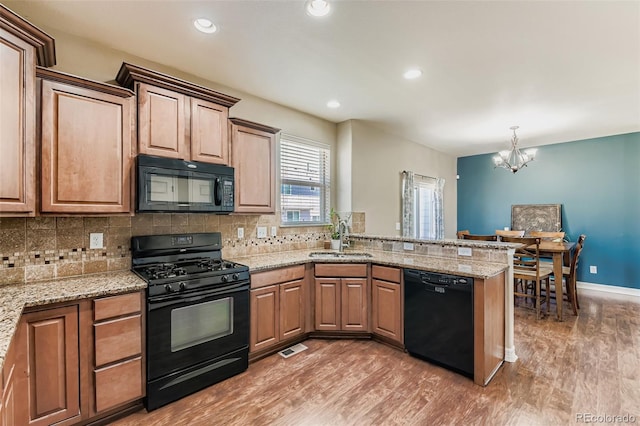12763 E 105th Pl, Commerce City, CO 80022 - kitchen with black appliances, a chandelier, light wood-style floors, a peninsula, and backsplash