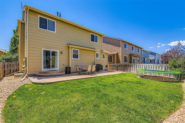 12763 E 105th Pl, Commerce City, CO 80022 - rear view of house with a trampoline, a fenced backyard, and a patio