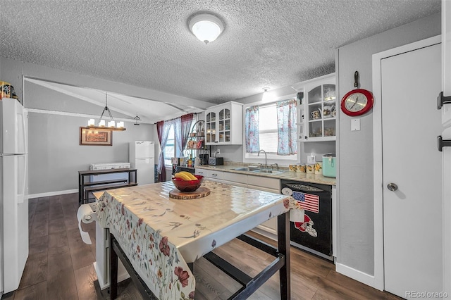 kitchen featuring lofted ceiling, white cabinetry, black dishwasher, white fridge, and sink