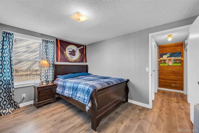 bedroom with a textured ceiling, hardwood / wood-style floors, and wooden walls