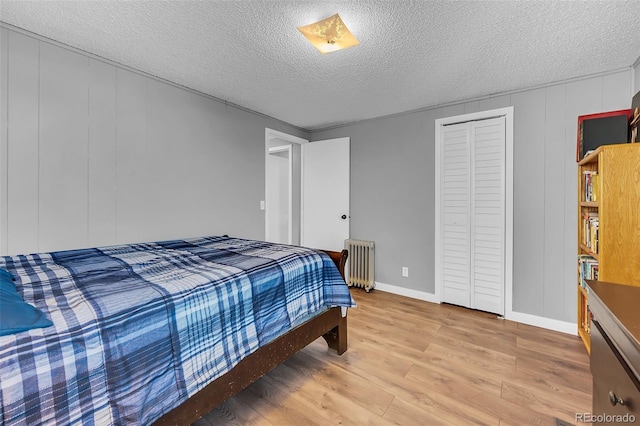 bedroom with hardwood / wood-style floors, radiator, a closet, and a textured ceiling