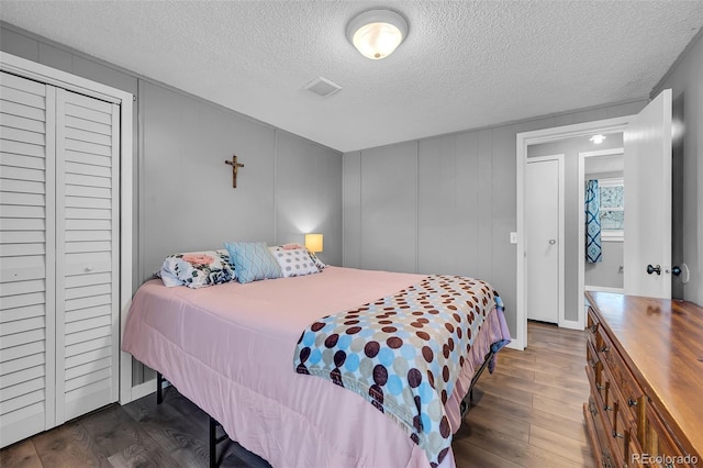 bedroom featuring a textured ceiling, a closet, and dark hardwood / wood-style flooring