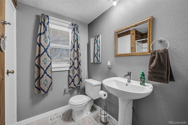 bathroom featuring a textured ceiling and toilet