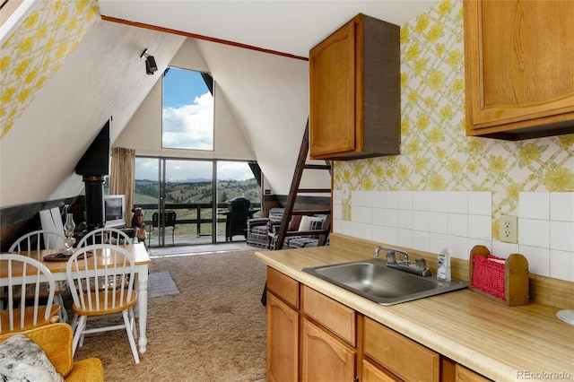 63 Welsh Cob Ln, Jefferson, CO 80456 - kitchen with light colored carpet, light countertops, vaulted ceiling, wallpapered walls, and brown cabinetry
