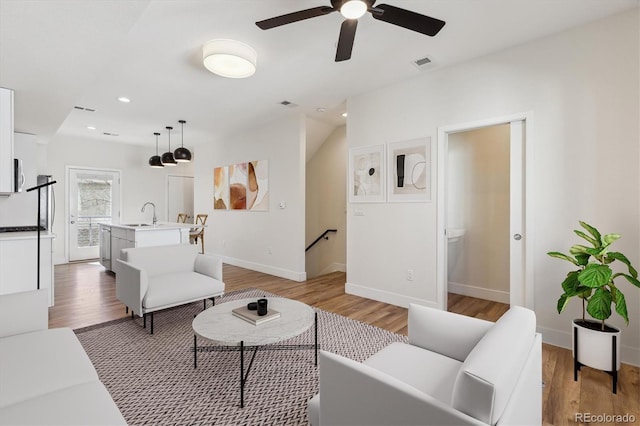 living room featuring light wood-type flooring, visible vents, baseboards, and recessed lighting