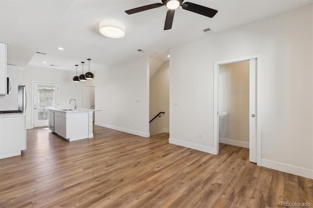 unfurnished living room featuring baseboards, visible vents, light wood-type flooring, a sink, and recessed lighting