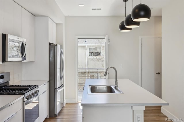 kitchen with appliances with stainless steel finishes, light countertops, a sink, and tasteful backsplash