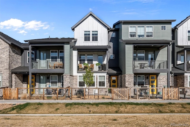 view of front of house featuring board and batten siding, a fenced front yard, stone siding, and a gate