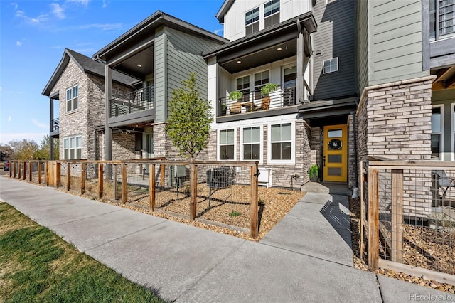 exterior space featuring board and batten siding, fence, and stone siding