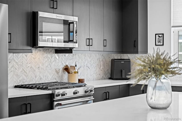 kitchen featuring gray cabinets, light countertops, decorative backsplash, and appliances with stainless steel finishes