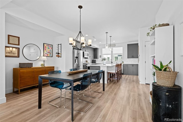 dining area featuring light wood-style flooring, a notable chandelier, and recessed lighting