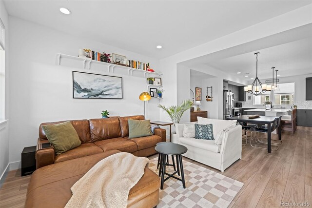 living area with light wood finished floors, an inviting chandelier, and recessed lighting