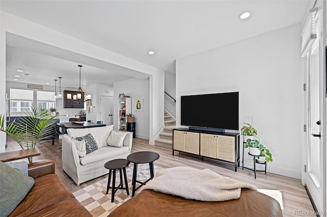 living area with light wood-type flooring, stairway, recessed lighting, and baseboards