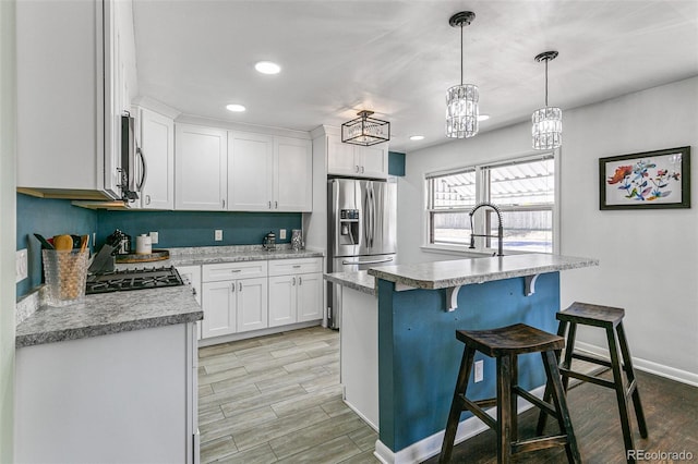 kitchen with light stone counters, pendant lighting, a breakfast bar area, white cabinets, and appliances with stainless steel finishes