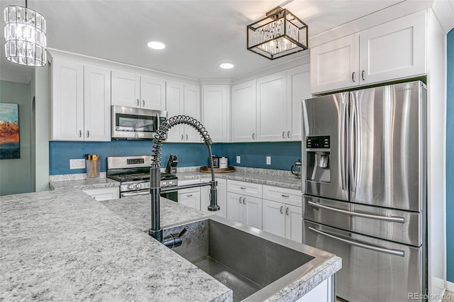 kitchen featuring appliances with stainless steel finishes, pendant lighting, light stone counters, sink, and white cabinetry