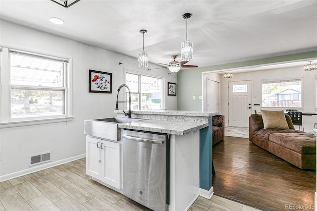 kitchen featuring a kitchen island with sink, hanging light fixtures, ceiling fan, white cabinets, and stainless steel dishwasher