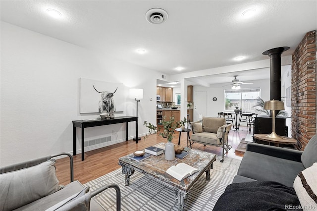 981 Ursula St, Aurora, CO 80011 - living area with light wood-type flooring, ceiling fan, baseboards, and a wood stove