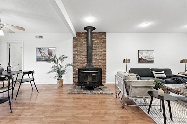 981 Ursula St, Aurora, CO 80011 - living room featuring a ceiling fan, light wood-type flooring, a wood stove, and baseboards