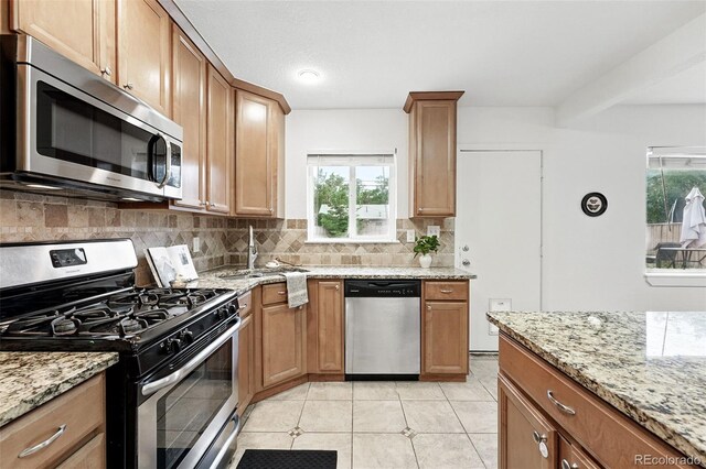 981 Ursula St, Aurora, CO 80011 - kitchen with appliances with stainless steel finishes, decorative backsplash, light stone counters, and a sink