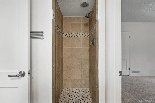 981 Ursula St, Aurora, CO 80011 - bathroom with a textured ceiling, tiled shower, and baseboards