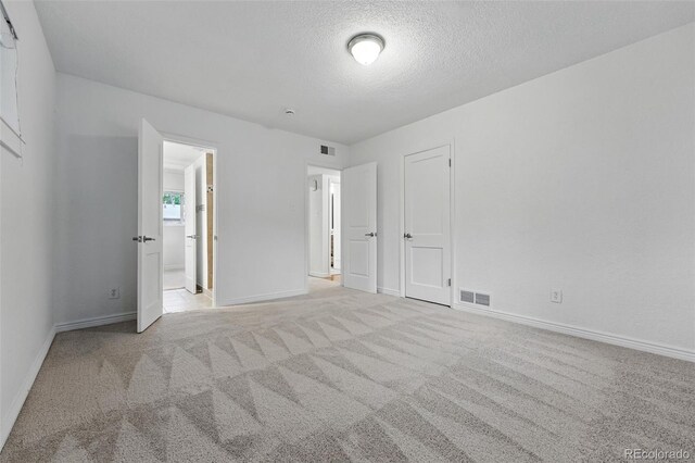 981 Ursula St, Aurora, CO 80011 - unfurnished bedroom with carpet flooring, baseboards, a textured ceiling, and connected bathroom