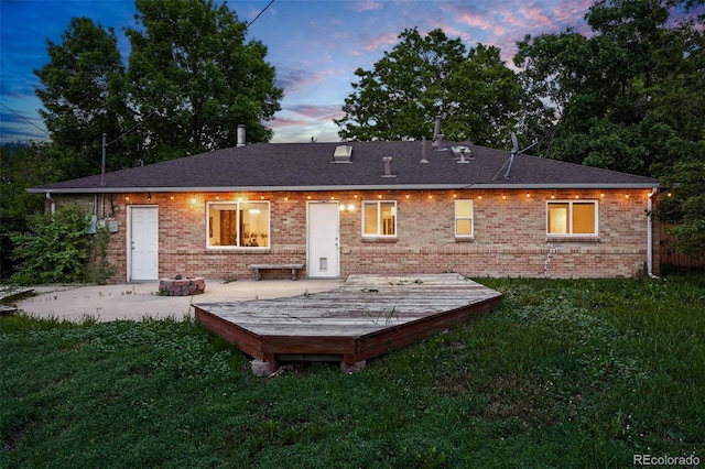 981 Ursula St, Aurora, CO 80011 - back of property at dusk featuring a yard, brick siding, and a deck