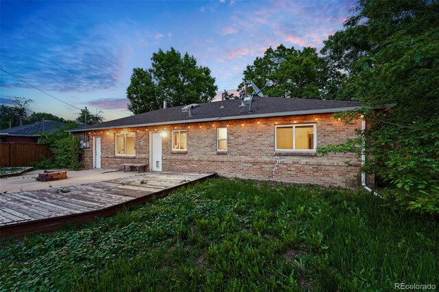 981 Ursula St, Aurora, CO 80011 - back of property at dusk featuring a fire pit, a wooden deck, and brick siding