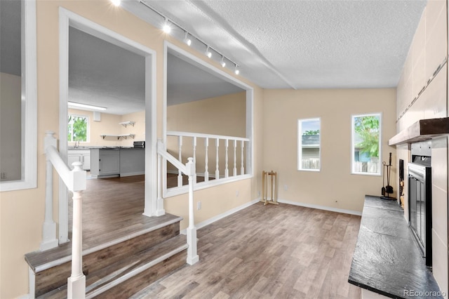 600 Bronco Rd, Denver, CO 80221 - unfurnished living room featuring wood finished floors, stairway, track lighting, radiator, and a textured ceiling