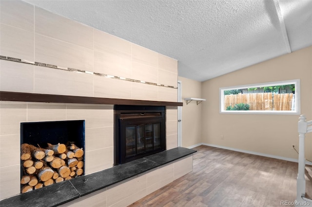 600 Bronco Rd, Denver, CO 80221 - unfurnished living room with wood finished floors, a fireplace, a textured ceiling, and vaulted ceiling