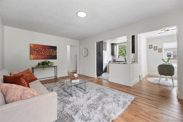 3344 W 33rd Ave, Denver, CO 80211 - living room featuring light wood-style flooring, baseboards, and a textured ceiling