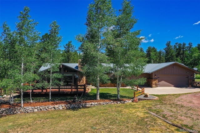 view of front of property with driveway, a front lawn, an attached garage, and stone siding