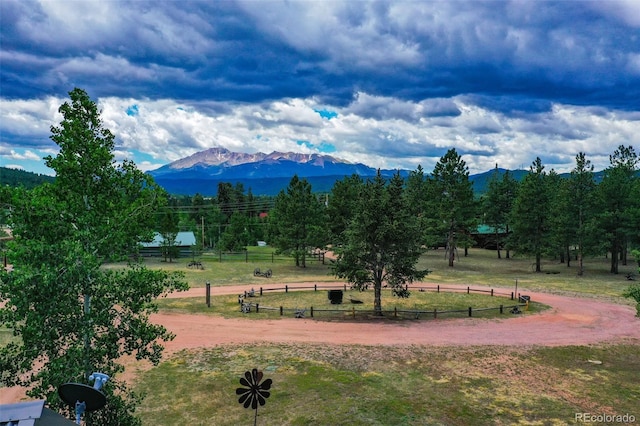 view of home's community with a yard, a rural view, fence, and a mountain view