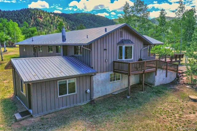 back of house featuring metal roof, board and batten siding, and a view of trees