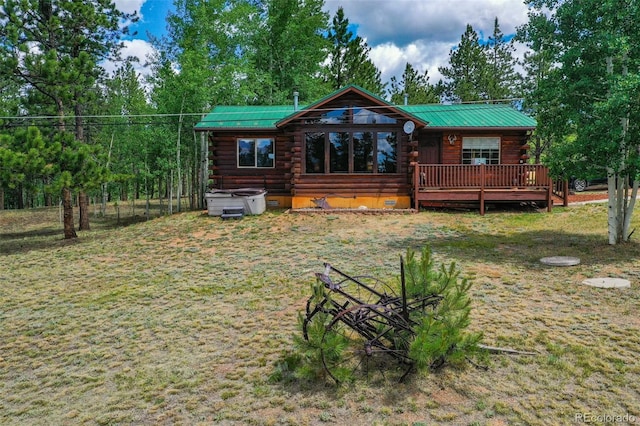 back of house with a hot tub, a wooden deck, and a lawn