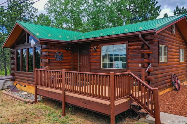 exterior space with metal roof, a wooden deck, and log siding