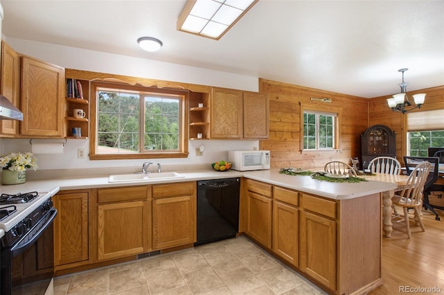 kitchen featuring pendant lighting, wood walls, white appliances, sink, and kitchen peninsula