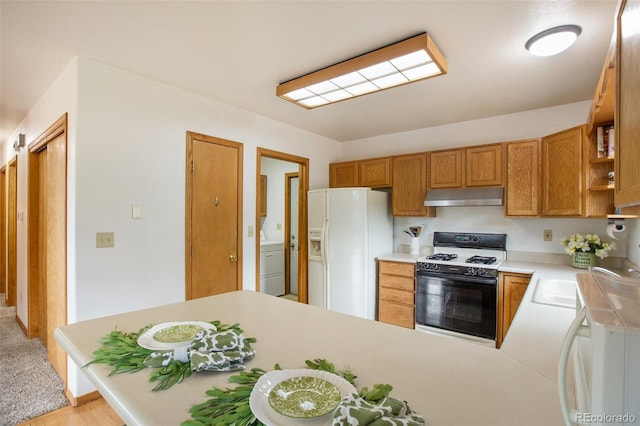 kitchen featuring white refrigerator with ice dispenser, range, a peninsula, light countertops, and under cabinet range hood