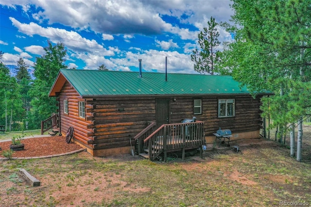 rear view of property with log siding, metal roof, and a lawn