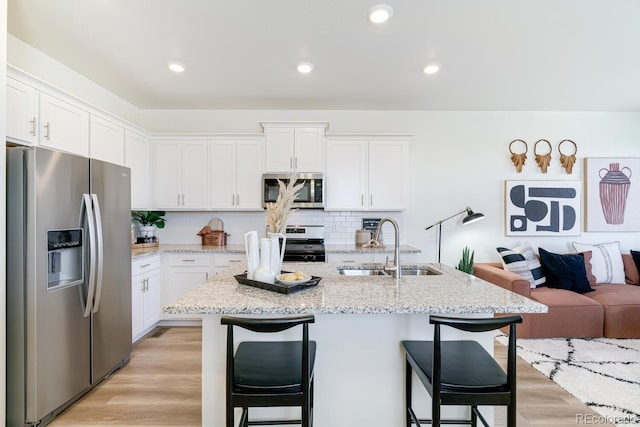 kitchen featuring stainless steel appliances, light wood-style floors, a sink, and a breakfast bar