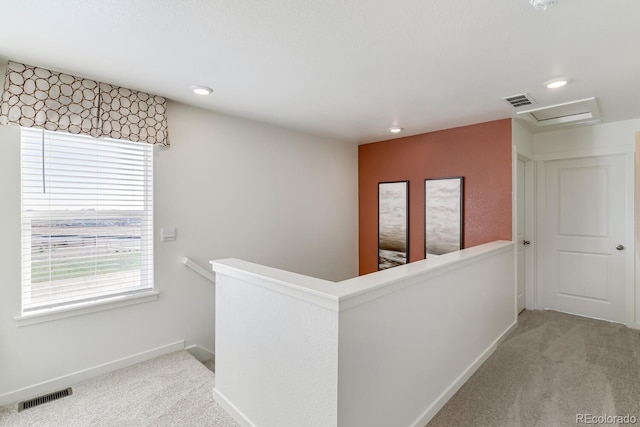 corridor featuring visible vents, carpet flooring, and an upstairs landing