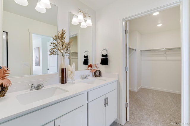 full bath with double vanity, a spacious closet, baseboards, and a sink