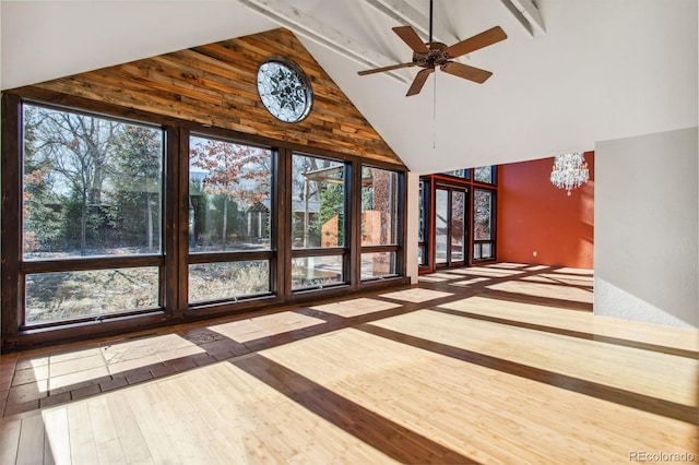 unfurnished sunroom featuring ceiling fan with notable chandelier and lofted ceiling with beams