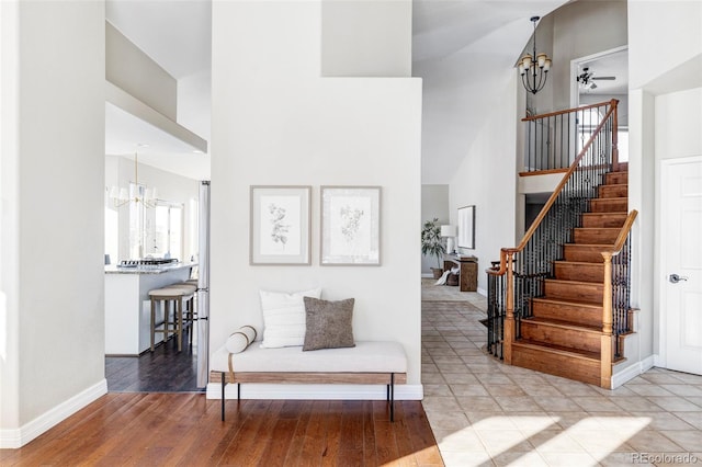 interior space featuring a high ceiling, wood-type flooring, and ceiling fan with notable chandelier