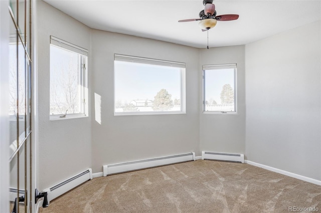 carpeted spare room with a baseboard radiator, a wealth of natural light, and ceiling fan