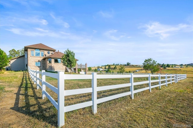 view of gate with a lawn and a rural view