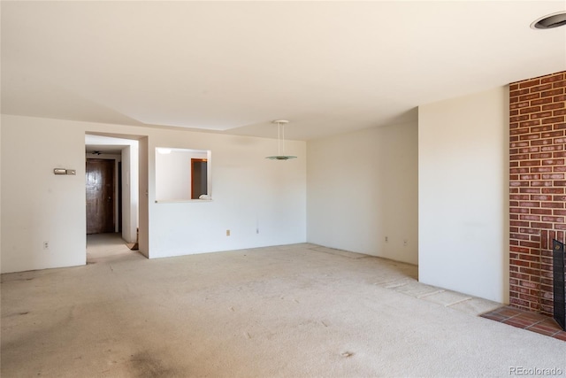 unfurnished room featuring a brick fireplace and light colored carpet