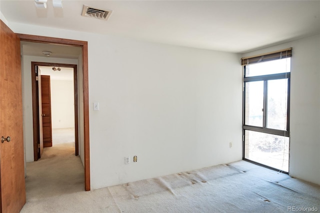 carpeted empty room featuring visible vents